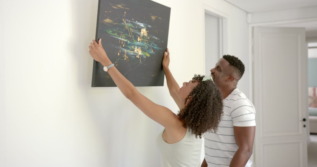 Couple Hanging Modern Art on Wall While Decorating Home