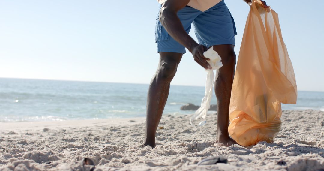Man Picking Up Trash on Beach Promoting Environmental Conservation
