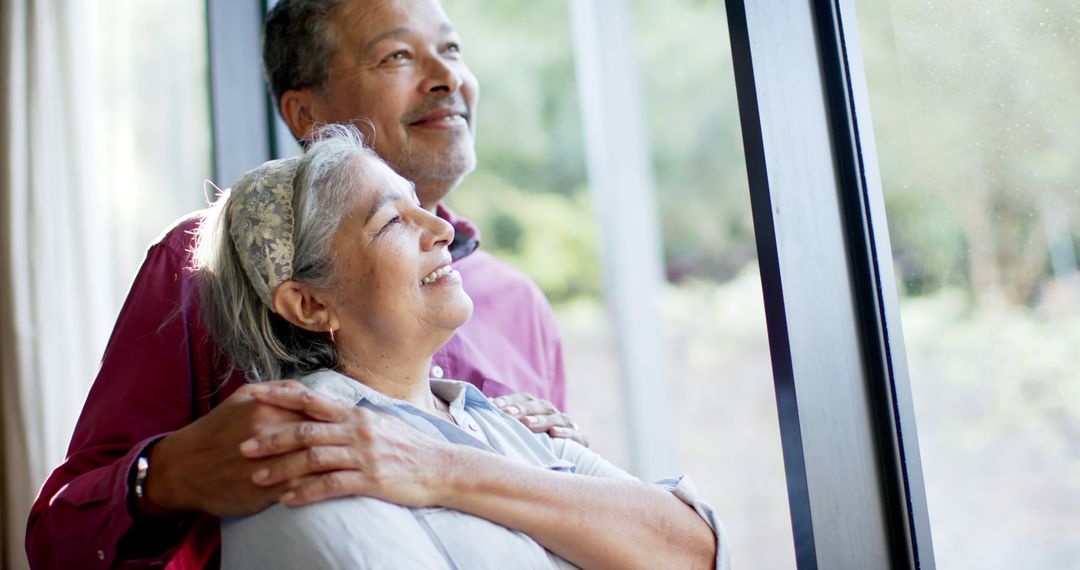 Happy Senior Couple Embracing by Window - Free Images, Stock Photos and Pictures on Pikwizard.com