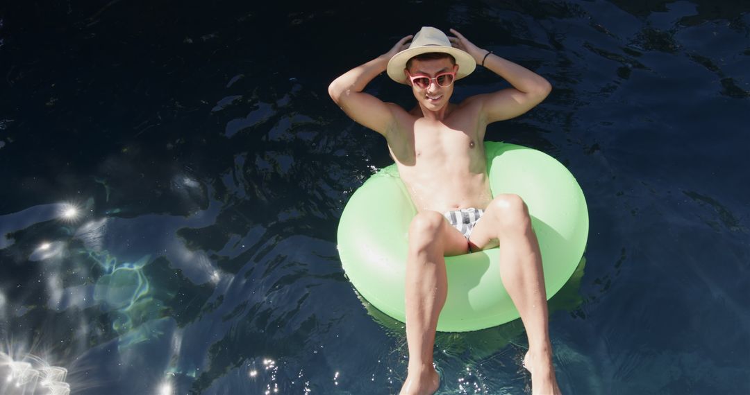 Young Man Relaxing on Pool Float Under Sun