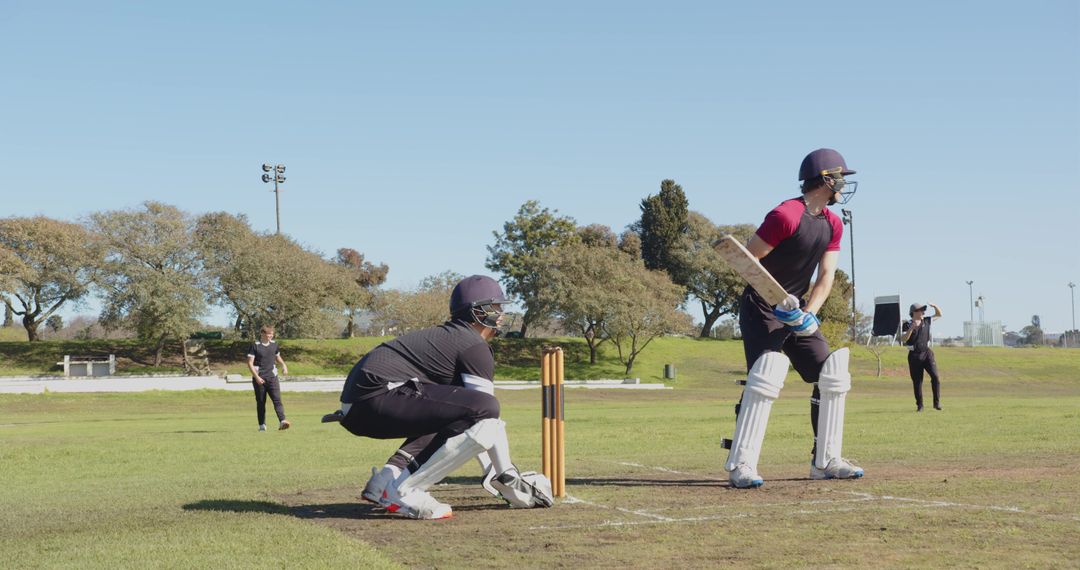 Cricketers in Action at Wicket on Sunny Outdoor Field