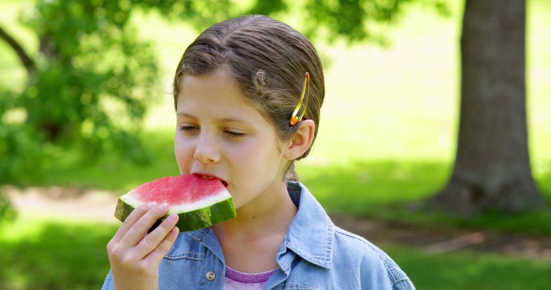 Cute little girl eating watermelon in the park on a sunny day - Free Images, Stock Photos and Pictures on Pikwizard.com