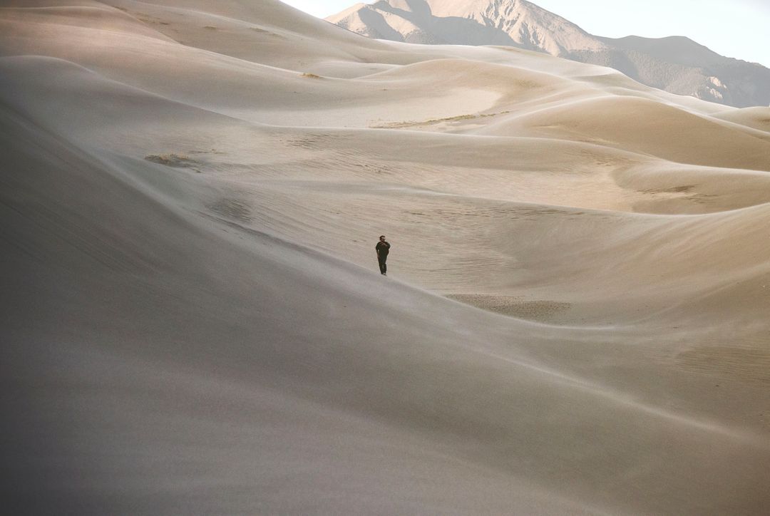Solitary Figure Walking Across Vast Desert Dunes - Free Images, Stock Photos and Pictures on Pikwizard.com