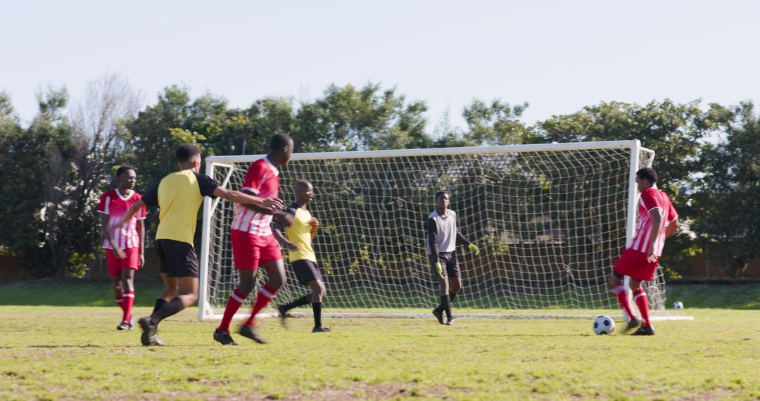 Diverse Soccer Players Competing Near Goal in Sunshine