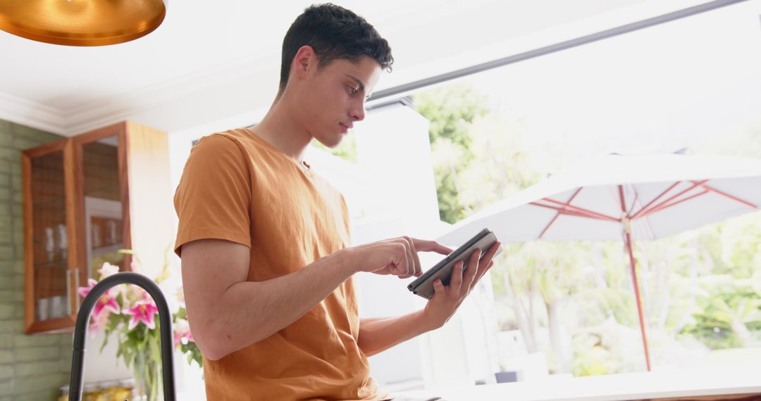 Young Man Engaging with Tablet by Sunlit Garden