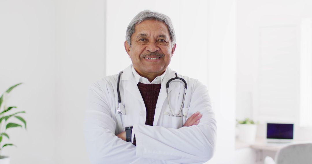 Smiling Senior Male Doctor Crossing Arms in Bright Medical Office - Free Images, Stock Photos and Pictures on Pikwizard.com