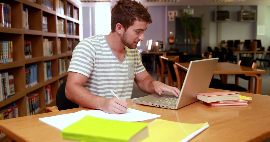 Young Man Studying on Laptop in Library Setting - Free Images, Stock Photos and Pictures on Pikwizard.com