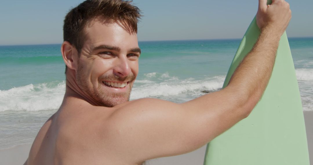 Smiling Man Holding Surfboard on Sunny Beach - Free Images, Stock Photos and Pictures on Pikwizard.com