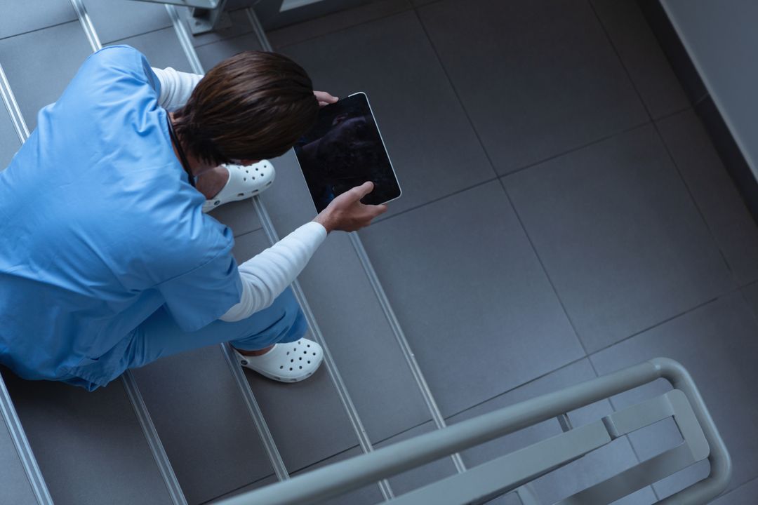 Male surgeon using digital tablet on stairs at hospital - Free Images, Stock Photos and Pictures on Pikwizard.com