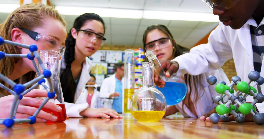 Students Collaborating in Chemistry Lab Pouring Colored Solutions for Science Class