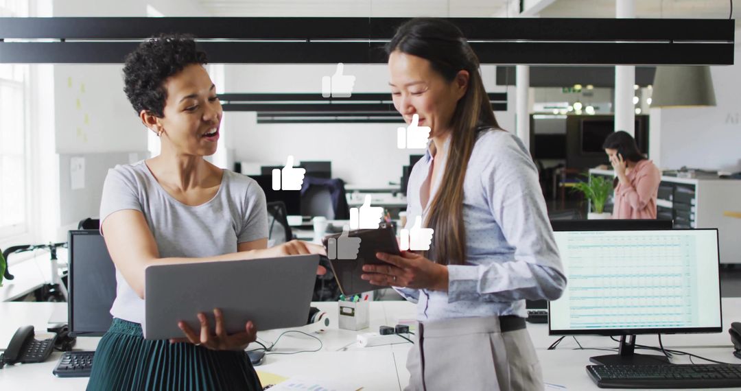 Colleagues collaborating with laptop and tablet in modern open-plan office with social likes