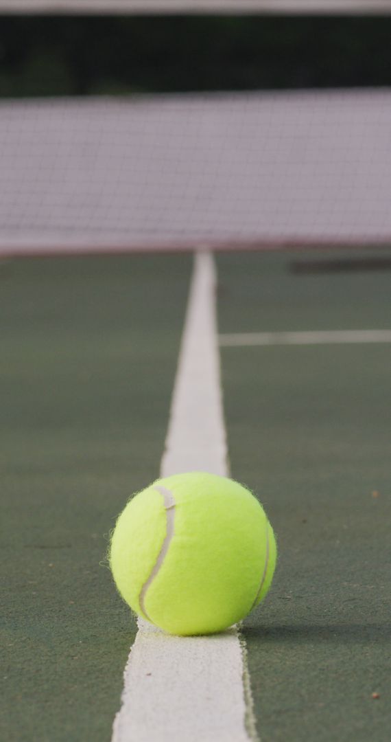 Yellow Tennis Ball on Green Outdoor Court with Net in Background - Free Images, Stock Photos and Pictures on Pikwizard.com