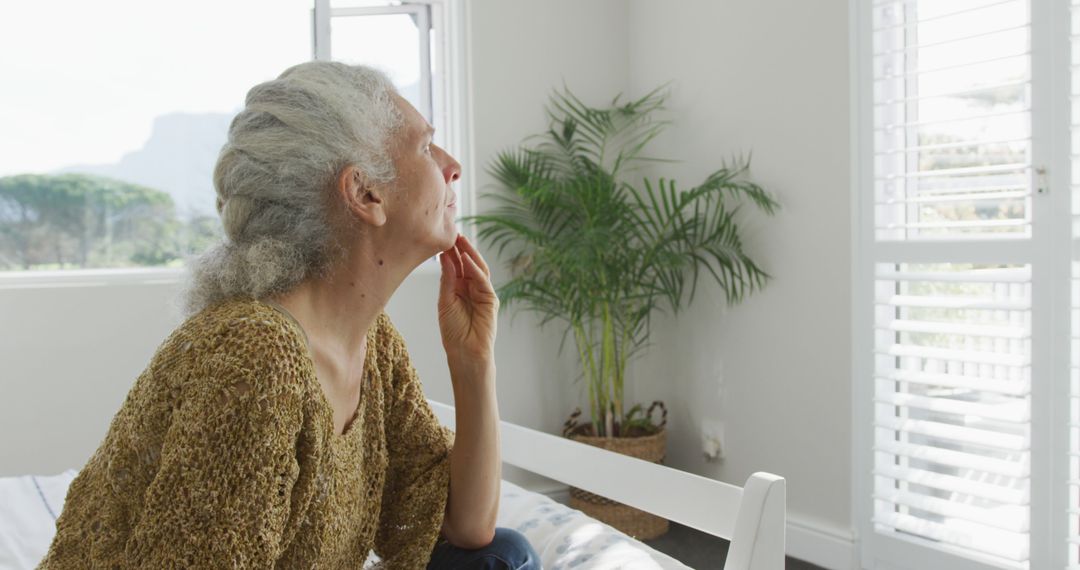 Senior Woman Reflecting by Window in Bright Room - Free Images, Stock Photos and Pictures on Pikwizard.com