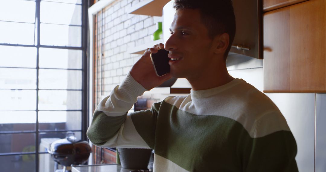 Smiling Young Man Talking on Smartphone in Modern Kitchen - Free Images, Stock Photos and Pictures on Pikwizard.com