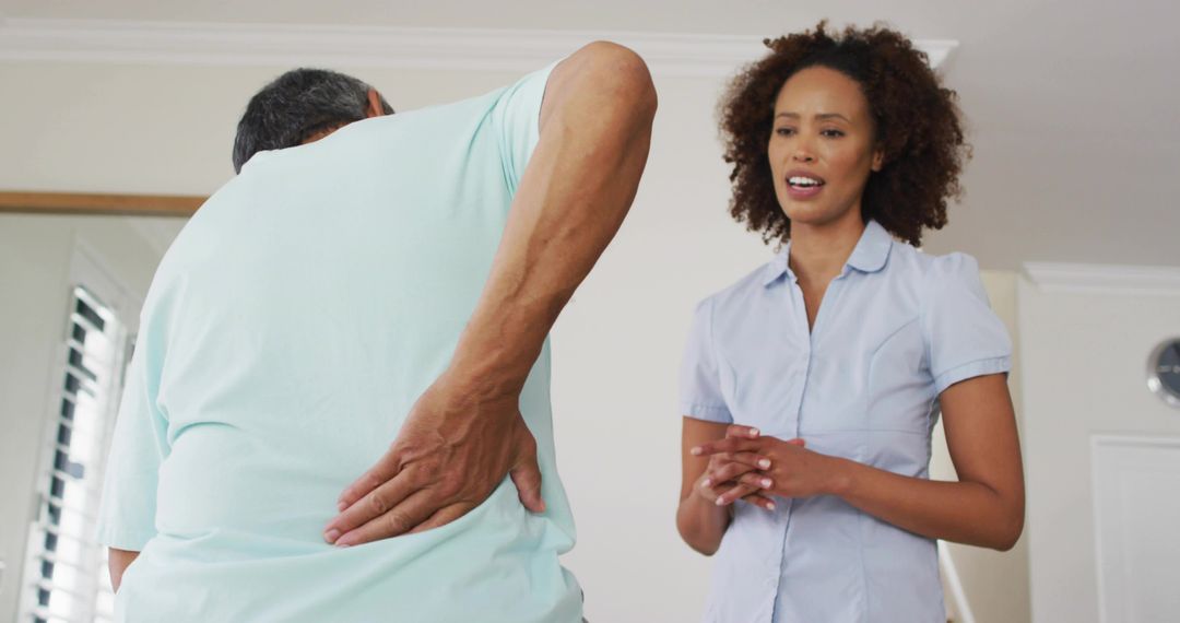 Caregiver Assisting Senior Man with Back Pain in Home Setting