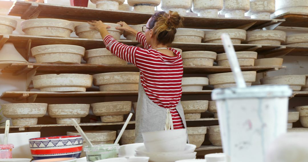 Woman in Pottery Studio Rearranging Ceramic Pieces on Shelves - Free Images, Stock Photos and Pictures on Pikwizard.com