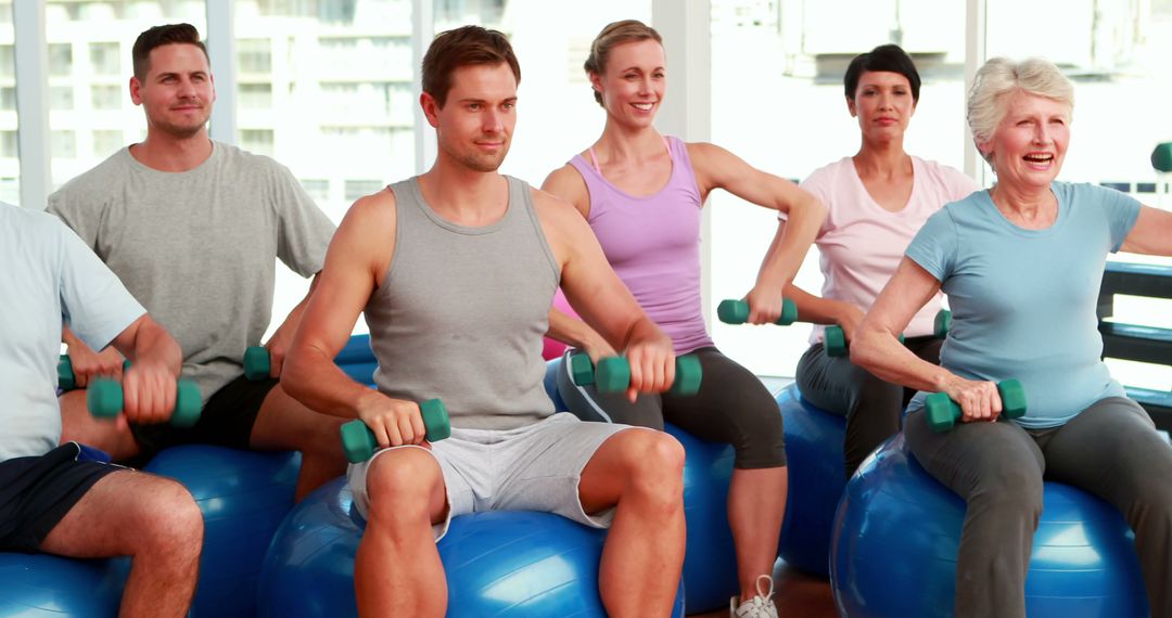 Fitness group sitting on exercise balls lifting hand weights at the gym - Free Images, Stock Photos and Pictures on Pikwizard.com