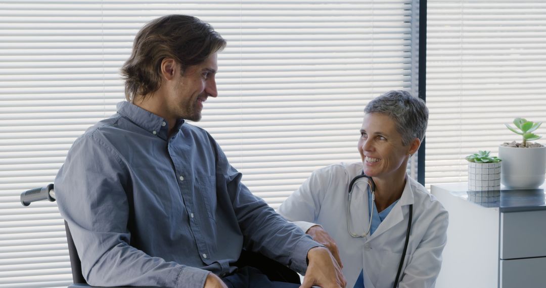 Smiling doctor encouraging male patient in wheelchair near window - Free Images, Stock Photos and Pictures on Pikwizard.com