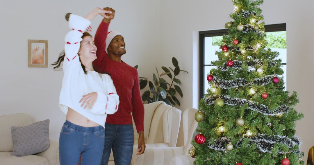 Diverse Couple Joyfully Dancing Near Christmas Tree at Home