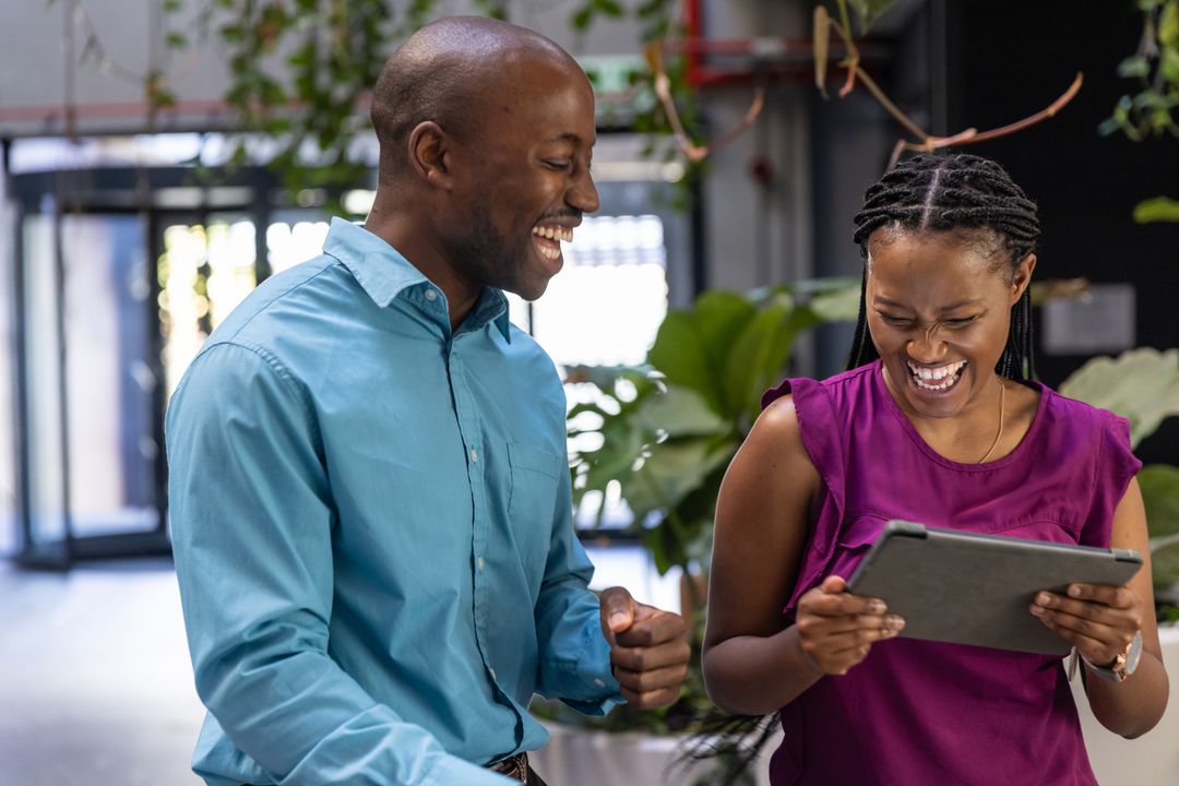 Smiling Colleagues Discussing Tablet in Modern Office