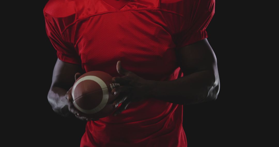 American Football Player Holding Ball in Low Light Studio - Free Images, Stock Photos and Pictures on Pikwizard.com