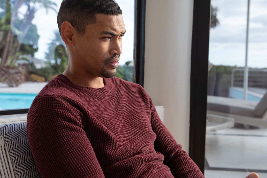 Pensive Man Gazing at Pool Through Glass Door