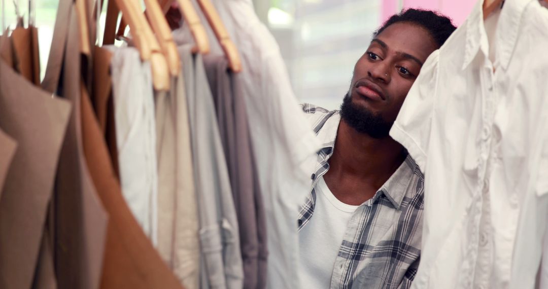 Man Browsing Clothes in Store with Focused Expression - Free Images, Stock Photos and Pictures on Pikwizard.com