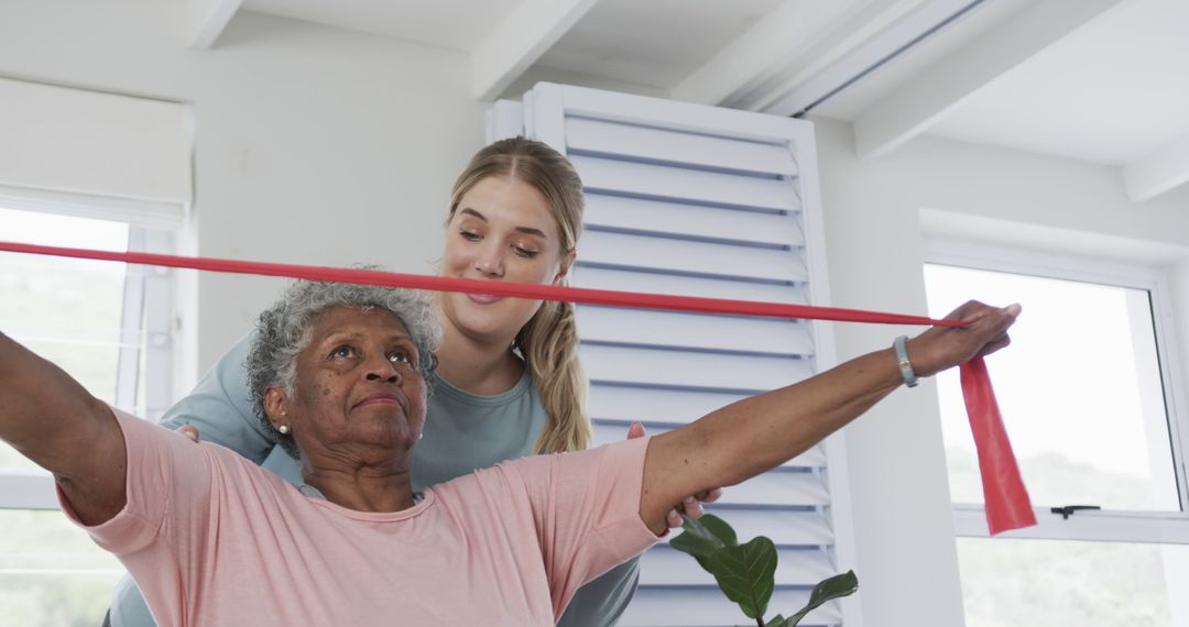 Elderly Woman Exercising with Therapist Using Resistance Band Indoors - Free Images, Stock Photos and Pictures on Pikwizard.com