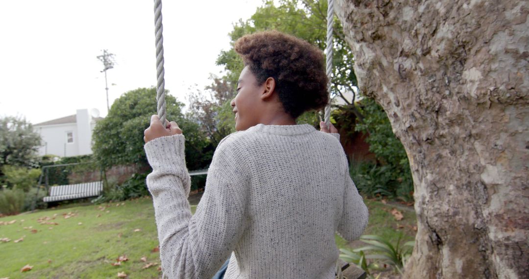 Joyful Boy Swinging on Tree Swing in Backyard Garden