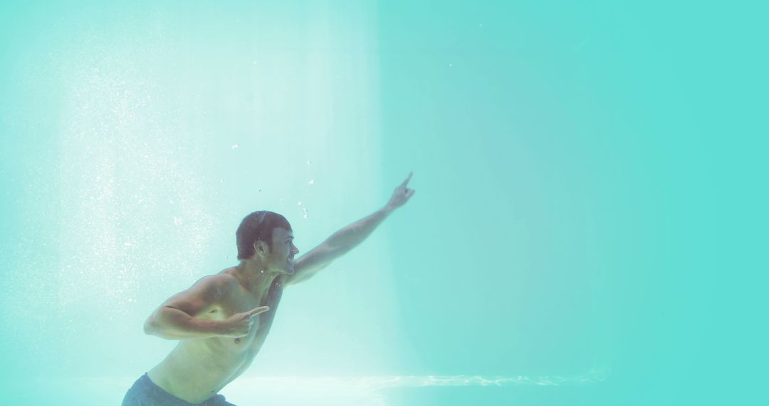 Man Underwater Pointing to the Sky in a Pool - Free Images, Stock Photos and Pictures on Pikwizard.com