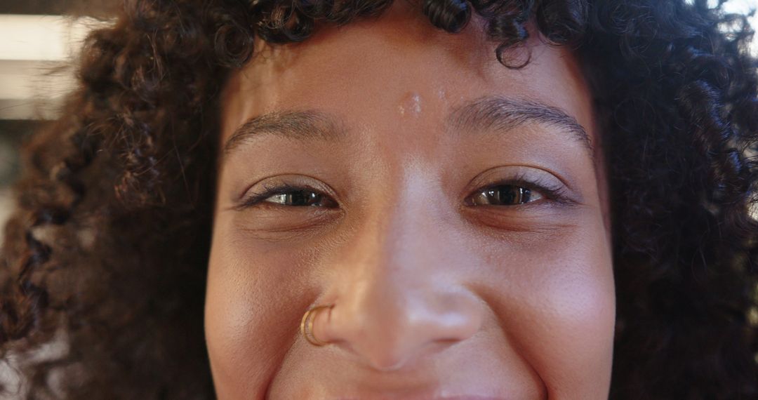 Close-Up of Smiling Woman with Curly Hair and Gold Nose Hoop