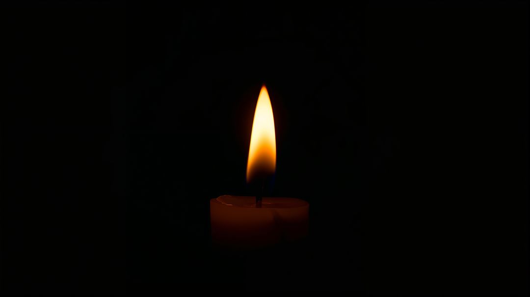 Single Burning Candle Flame with Warm Teardrop Glow and Blue Base on Deep Black Background