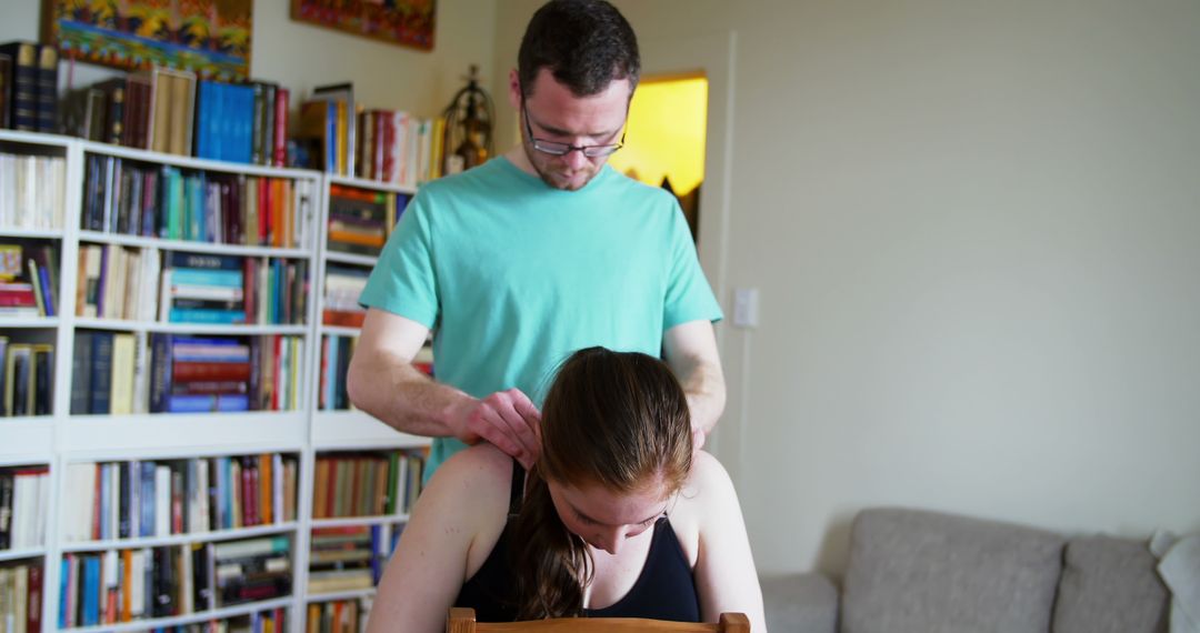 Man giving woman neck massage in cozy home library - Free Images, Stock Photos and Pictures on Pikwizard.com