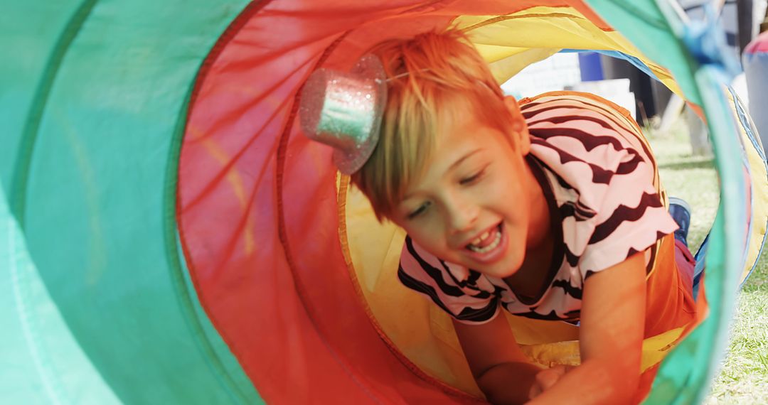 Child playing inside colorful play tunnel at outdoor event - Free Images, Stock Photos and Pictures on Pikwizard.com