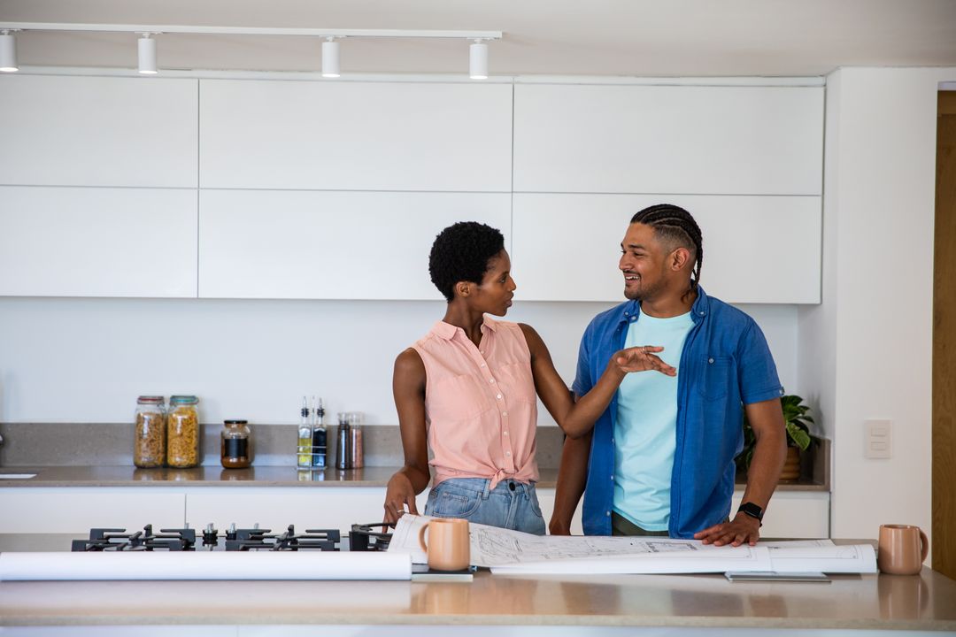 Multicultural Couple Discussing Home Blueprints in Modern Kitchen