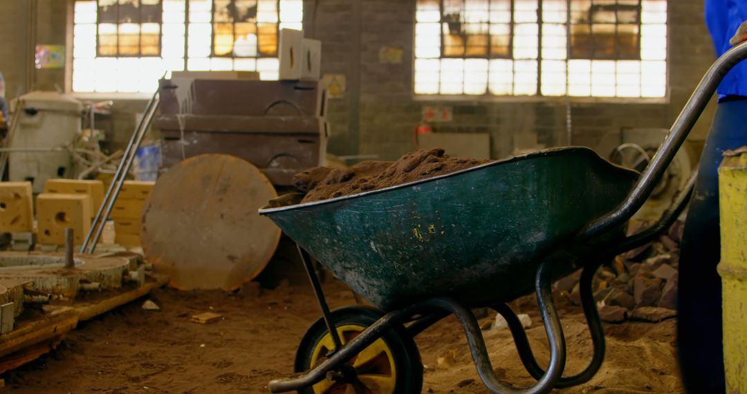 Worker Using Wheelbarrow in Industrial Workshop - Free Images, Stock Photos and Pictures on Pikwizard.com