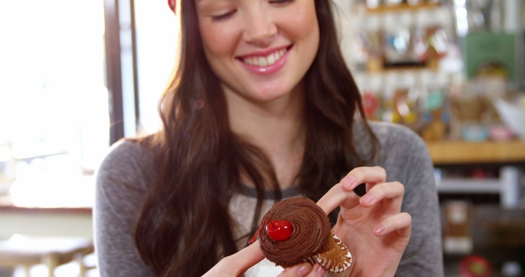 Smiling Woman Holding Chocolate Cupcake with Red Cherry - Free Images, Stock Photos and Pictures on Pikwizard.com