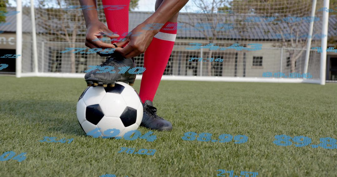 Male Soccer Player Tying Cleat on Ball Preparing for Goal Kick on Artificial Turf