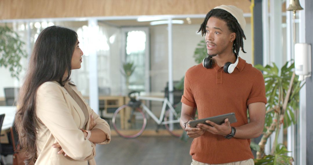 Multicultural Coworkers Collaborating in Modern Open Office Holding Tablet and Headphones