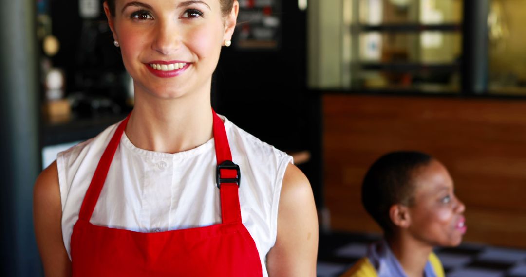 Smiling Woman in Red Apron Working in Cafe - Free Images, Stock Photos and Pictures on Pikwizard.com