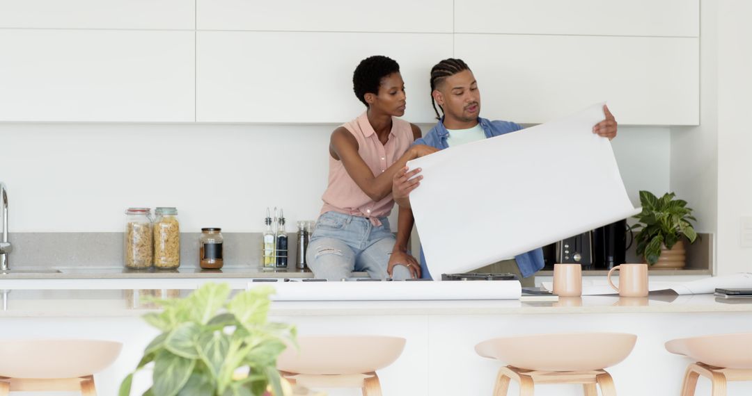 Diverse Couple Reviewing Blueprint on Modern Kitchen Counter Island
