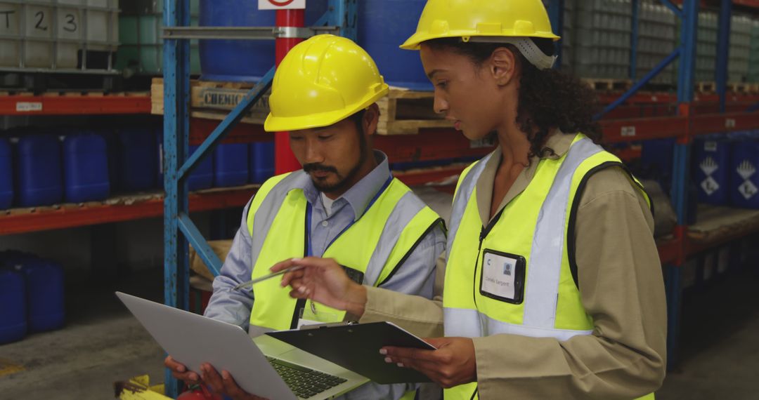 Warehouse Workers Wearing Safety Gear Using Laptop and Clipboard - Free Images, Stock Photos and Pictures on Pikwizard.com