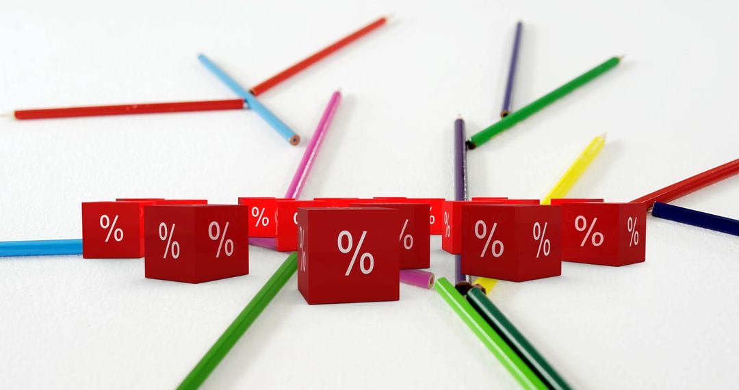 Red Percentage Cubes Surrounded by Mixed Color Pencils on White Surface