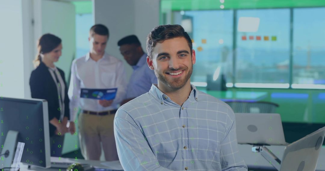 Smiling Young Professional Leaning at Desk with Team Reviewing Report in Modern Office