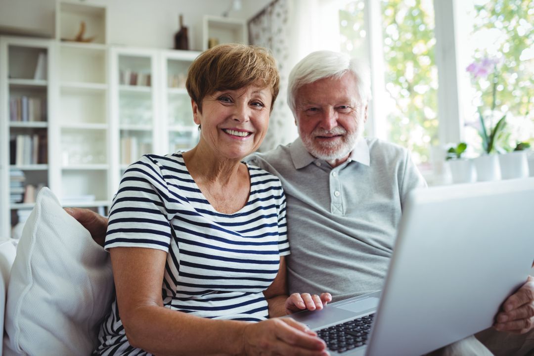 Happy Senior Couple Using Laptop in Bright Living Room - Free Images, Stock Photos and Pictures on Pikwizard.com