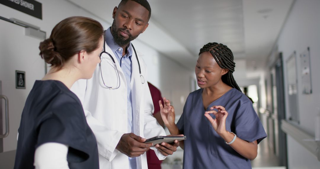 Medical Team Discussing Patient Care with Tablet in Hospital Hallway - Free Images, Stock Photos and Pictures on Pikwizard.com