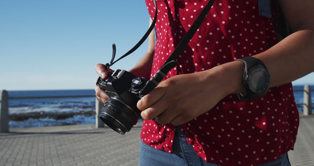 Woman Holding Camera Near Sea in Warm Weather - Free Images, Stock Photos and Pictures on Pikwizard.com