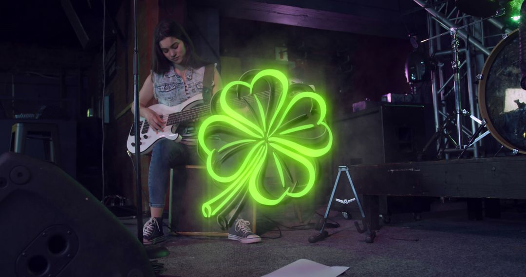 Image of st patrick's day green shamrock neon over woman playing guitar on stage - Free Images, Stock Photos and Pictures on Pikwizard.com