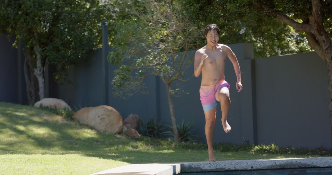 Young Man Jumping Into Pool Enjoying Summer Sunshine