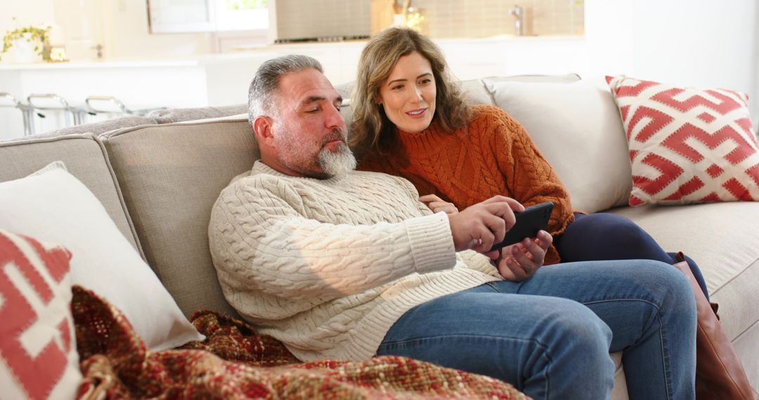 Middle-aged Couple Relaxing on Sofa Sharing Smartphone in Cozy Modern Living Room